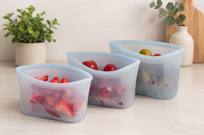 Set of blue reusable silicone storage containers filled with strawberries, grapes, and cherry tomatoes