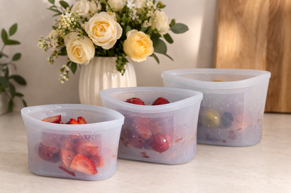 Reusable blue silicone food storage bags with fresh fruit on a wooden kitchen countertop
